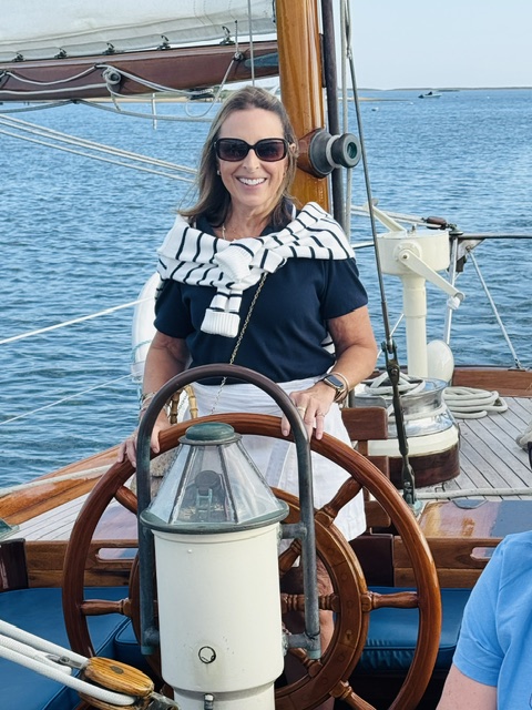 women with striped sweater steering boat