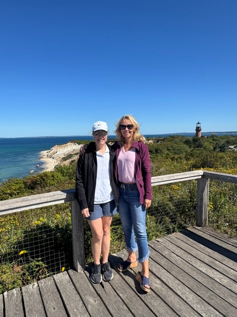 two women smiling in front of lighthouse