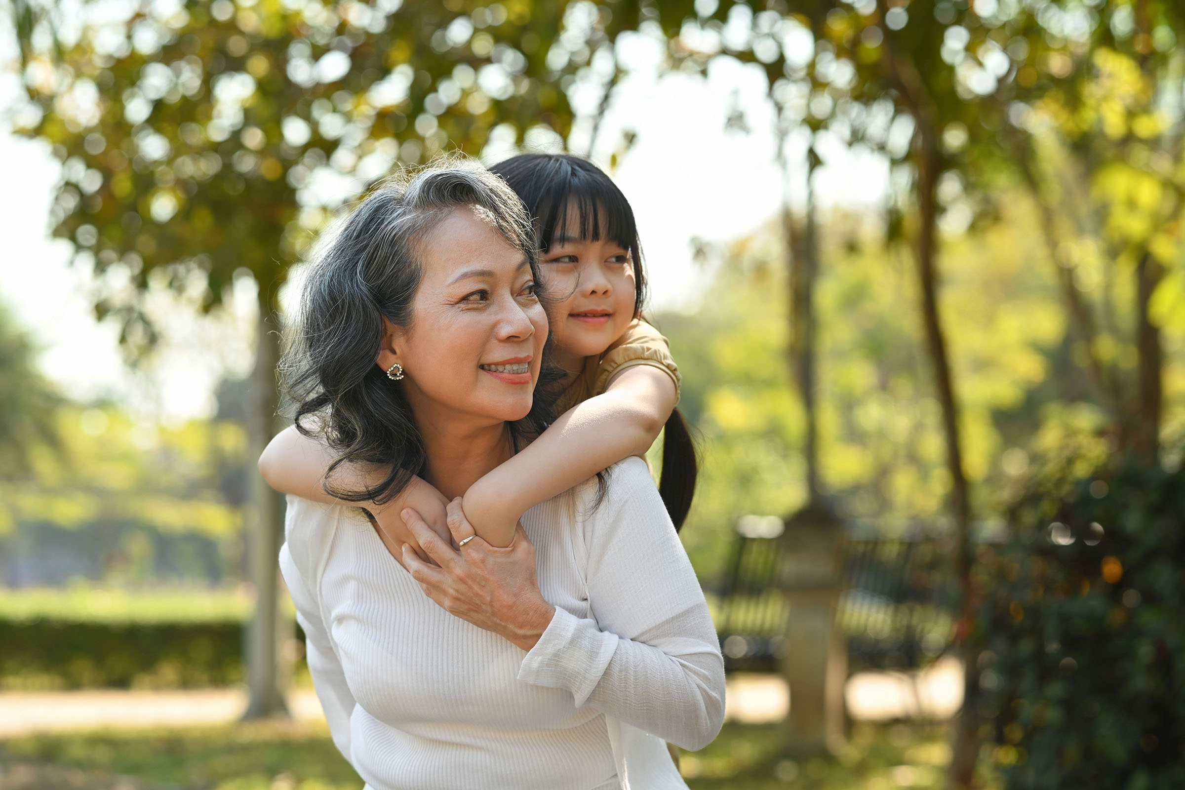 Smiling mature grandmother giving piggyback ride to cute grandaughter