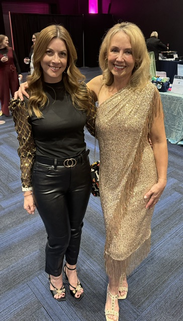 Woman in gold dress standing next to woman in black leather pants