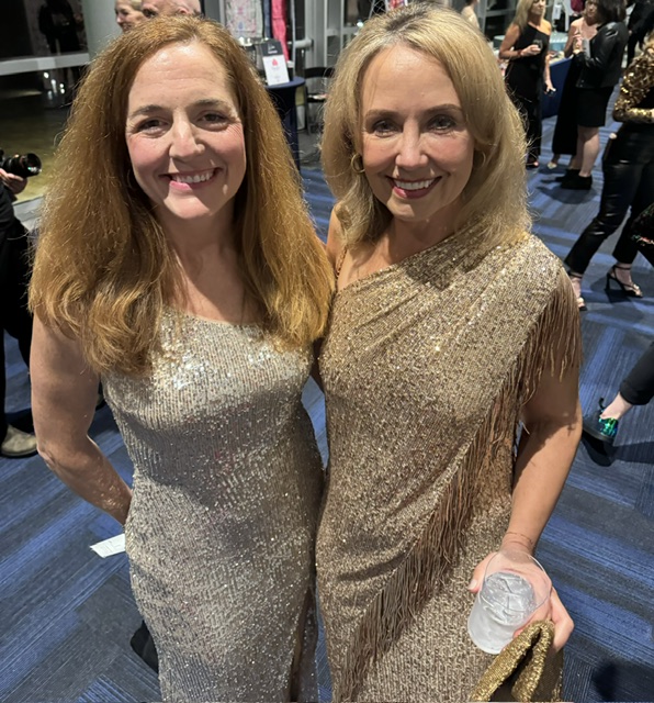 Two women in metallic dresses standing next to each other